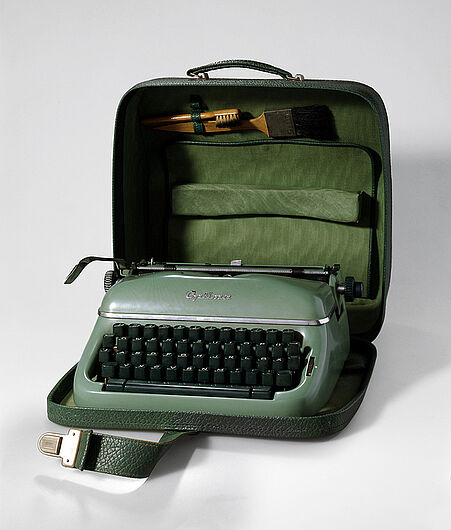 Kleinschreibmaschine „Optima Elite 3“ mit Reinigungszubehör, ab 1955. Die Schreibmaschine war ein „Messe- und Exportschlager“. Das Optima-Werk zeigte sie auf den Leipziger Messen und auf anderen internationalen Ausstellungen in Singapur, Kairo oder Düsseldorf. (Inv.Nr. HI 90/21)