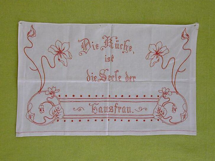Ein mit Text und floralen Motiven bestickter Stoff.