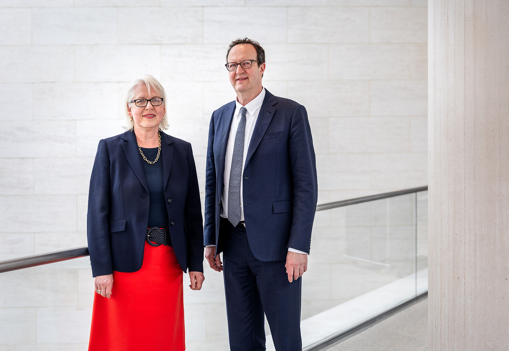 Zwei Personen stehen nebeneinander in einem Museum und schauen freundlich in die Kamera.
