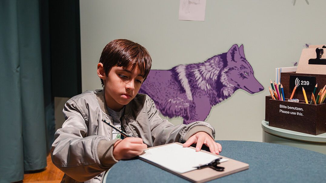 Ein Kind sitzt in einer Ausstellung und malt.