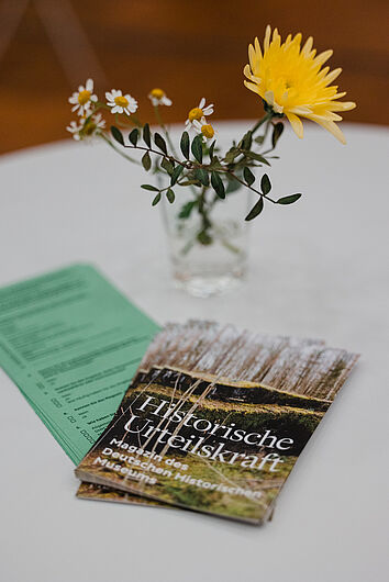 Flyer, Magazine des DHMs und Blumen in einer Vase auf einem Tisch.