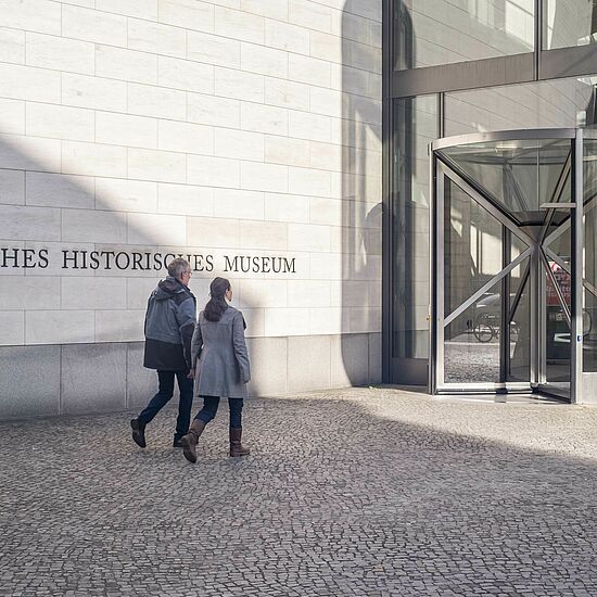 Eine Frau und ein Mann laufen Richtung Eingang des DHMs.