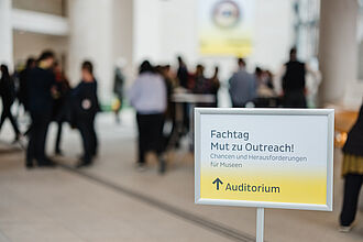 Ein Schild mit der Aufschrift "Fachtag" vor einer Menschenmenge