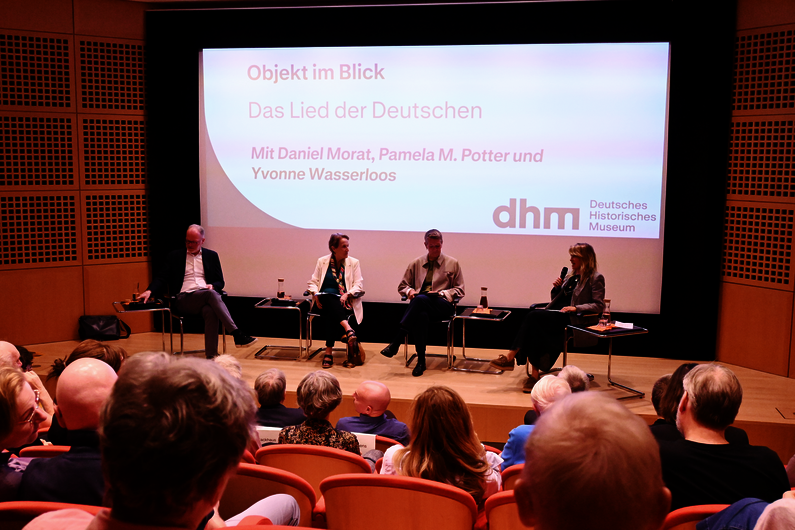 Vier Personen sitzen auf einer Bühne und diskutieren