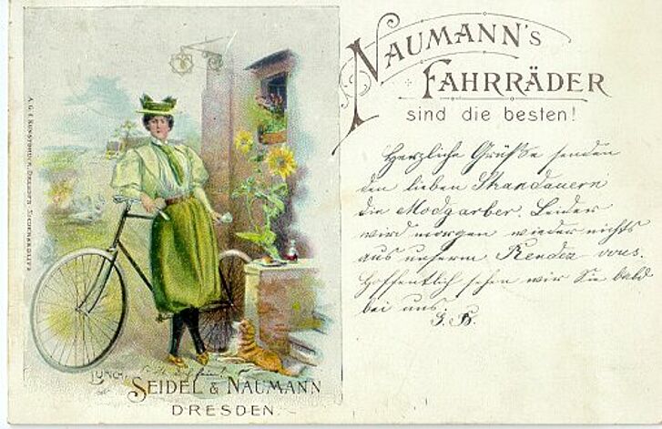 Postkarte mit Frau, die vor einem Rad steht.