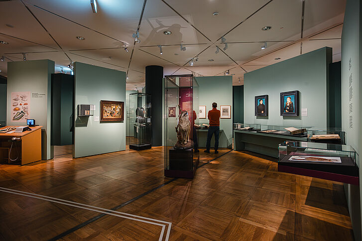 Exhibition view "Nature and German History. Faith – Biology – Power" Man in red sweater viewing exhibition