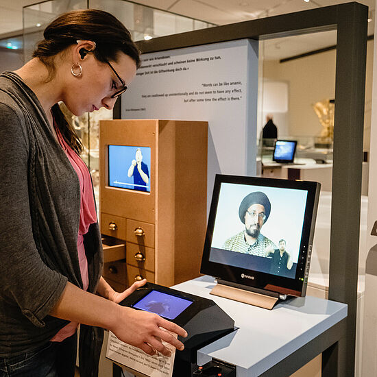 Eine Person betrachtet eine Interaktive Kommunikationsstation in einer Ausstellung.