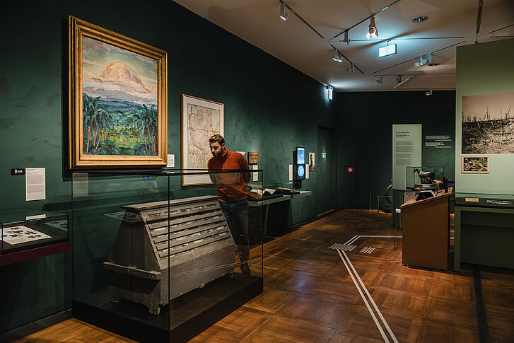 Exhibition view "Nature and German History. Faith – Biology – Power" A man in a red sweater looks at the Wardian case.