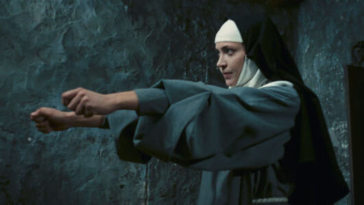 Eine Nonne streckt beide Arme aus und ballt Fäuste.