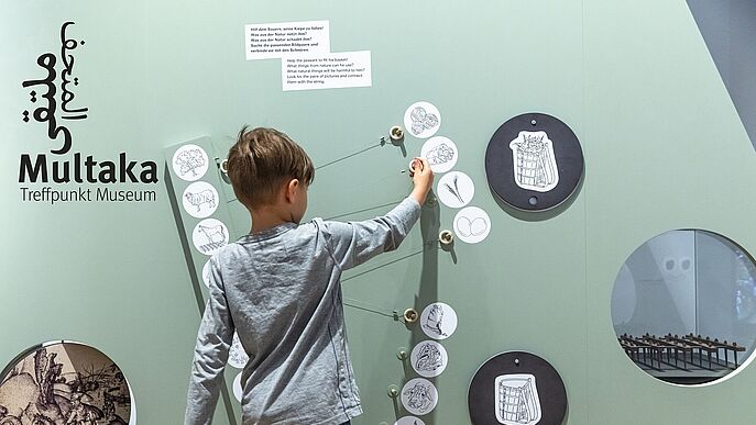 Ein Junge betätigt ein Objekt an einer Ausstellungwand.