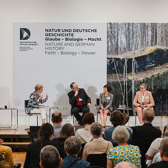 Vier Personen sitzen auf der Bühne und führen ein Gespräch.