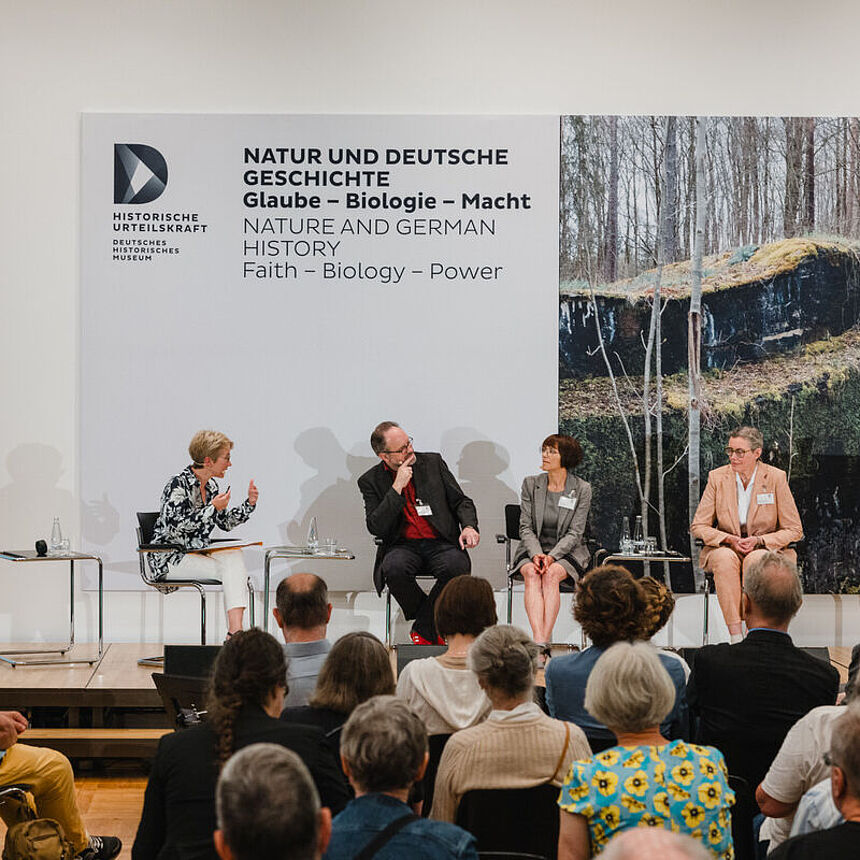 Vier Personen sitzen auf der Bühne und führen ein Gespräch.