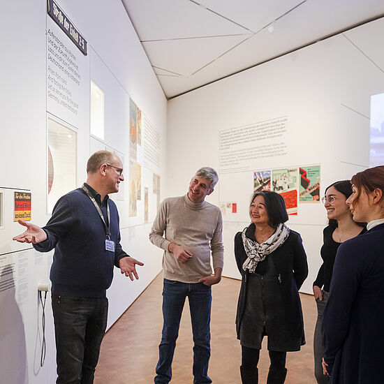 Ein Mann gibt eine Führung und steht vor einer Ausstellungswand.