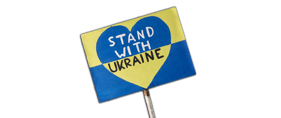 Demonstrationsschild aus Pappe mit einem Stiel, das in den Nationalfarben der Ukraine Blau und Gelb angemalt wurde. In der Mitte ist ein Herz indem "Stand with Ukraine" steht.