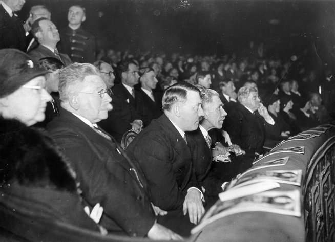 [Foto: Ehrengäste der Uraufführung des Ufa-Films "Morgenrot" im Berliner Ufa-Palast am Zoo. Adolf Hitler zwischen Alfred Hugenberg und Franz von Papen (rechts), 1933]