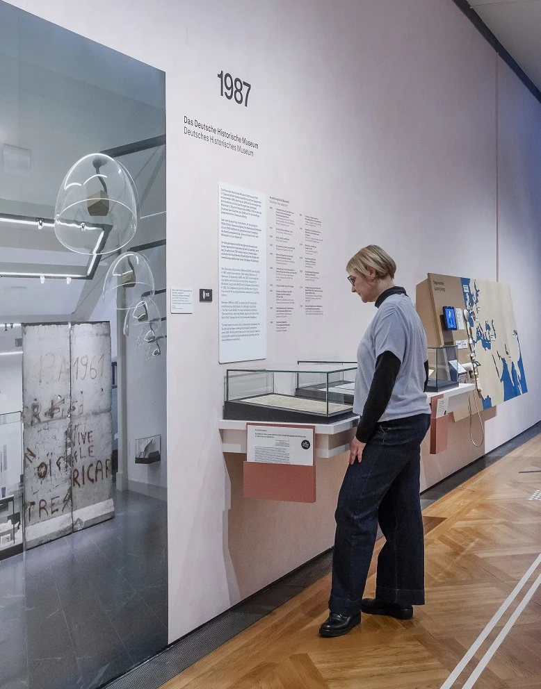Eine Frau steht in einer Ausstellung und schaut sich ein Dokument in einer Vitrine an.