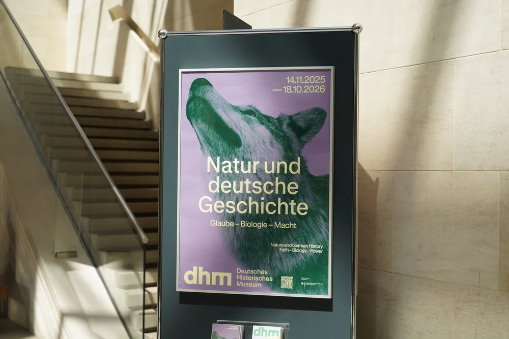 Ausstellungsplakat mit einem präparierten Wolf im Zentrum. Darauf der Schriftzug „Natur und deutsche Geschichte. Glaube - Biologie - Macht"