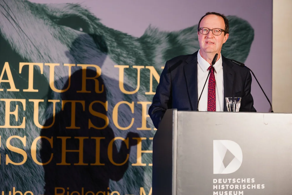 Eine Person steht an einem Pult und spricht in ein Mikrofon