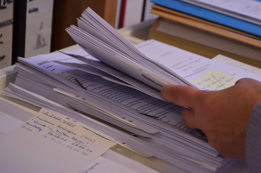 Eine Hand hält Verträge und andere Unterlagen