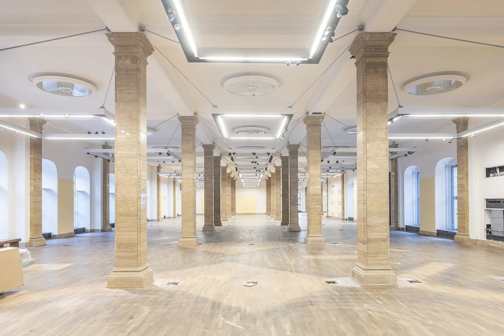 A large, empty exhibition space divided by columns.