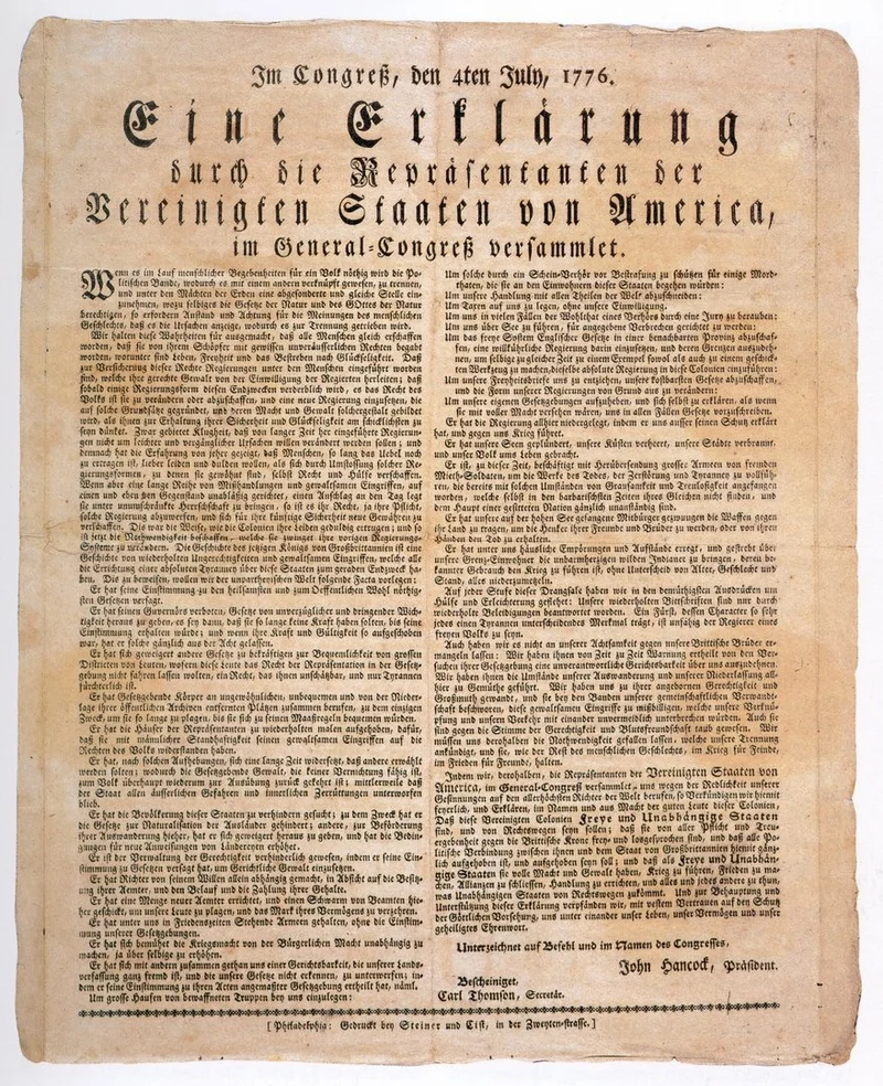 Historisches Druckdokument auf vergilbtem Papier. Überschrift in Frakturschrift: „Im Congreß, den 4ten July, 1776. Eine Erklärung durch die Repräsentanten der Vereinigten Staaten von America, im General-Congreß versammlet.“ Darunter engbedruckter Fließtext in zwei Spalten, am unteren Rand Unterschriften, darunter „John Hancock, Präsident“. Das Papier zeigt deutliche Alterungsspuren mit leichter Bräunung und unregelmäßigen Rändern.