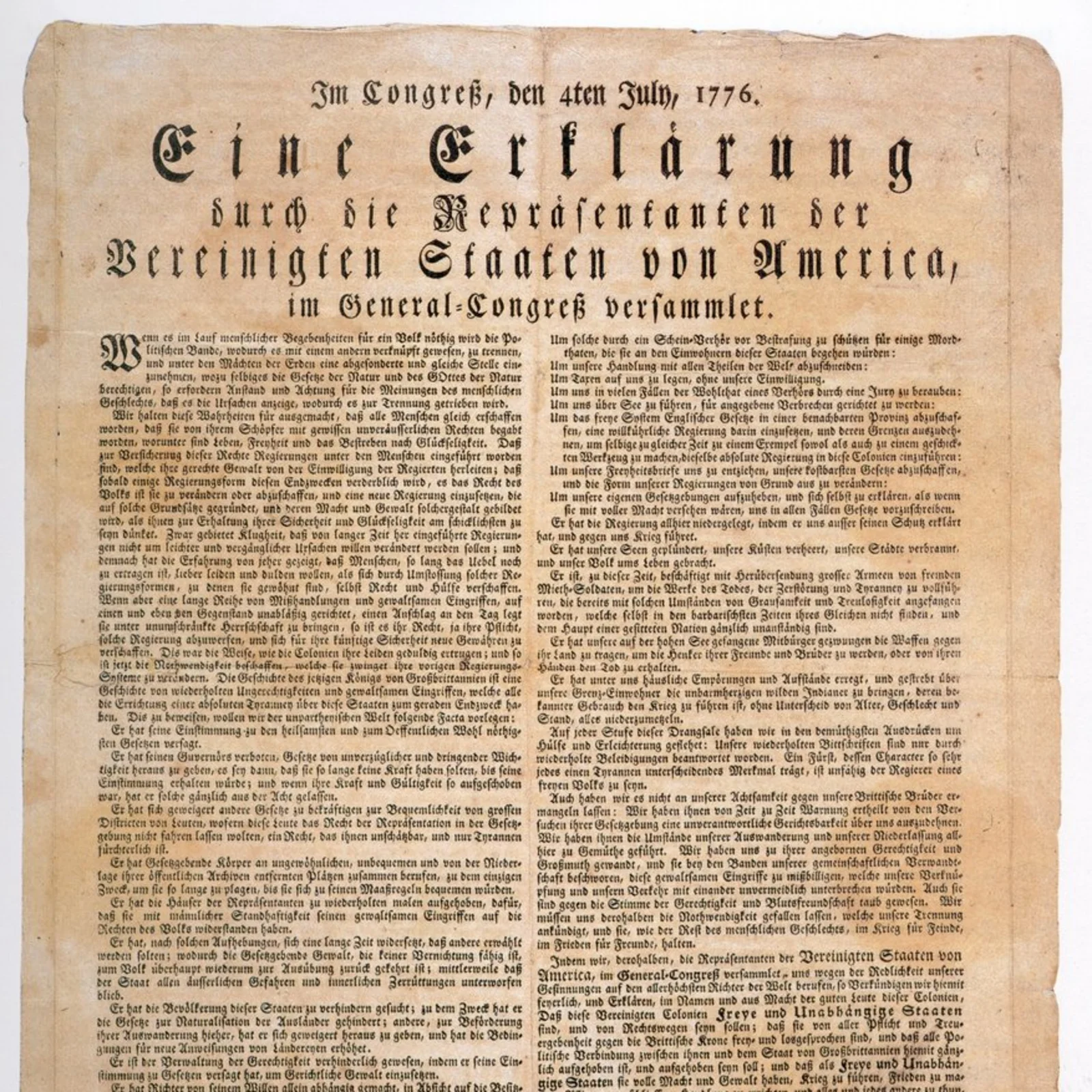 Historisches Druckdokument auf vergilbtem Papier. Überschrift in Frakturschrift: „Im Congreß, den 4ten July, 1776. Eine Erklärung durch die Repräsentanten der Vereinigten Staaten von America, im General-Congreß versammlet.“ Darunter engbedruckter Fließtext in zwei Spalten, am unteren Rand Unterschriften, darunter „John Hancock, Präsident“. Das Papier zeigt deutliche Alterungsspuren mit leichter Bräunung und unregelmäßigen Rändern.