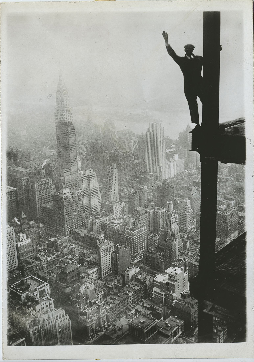 Ein Arbeiter grüßt von einem Eisenträger des Empire State Building