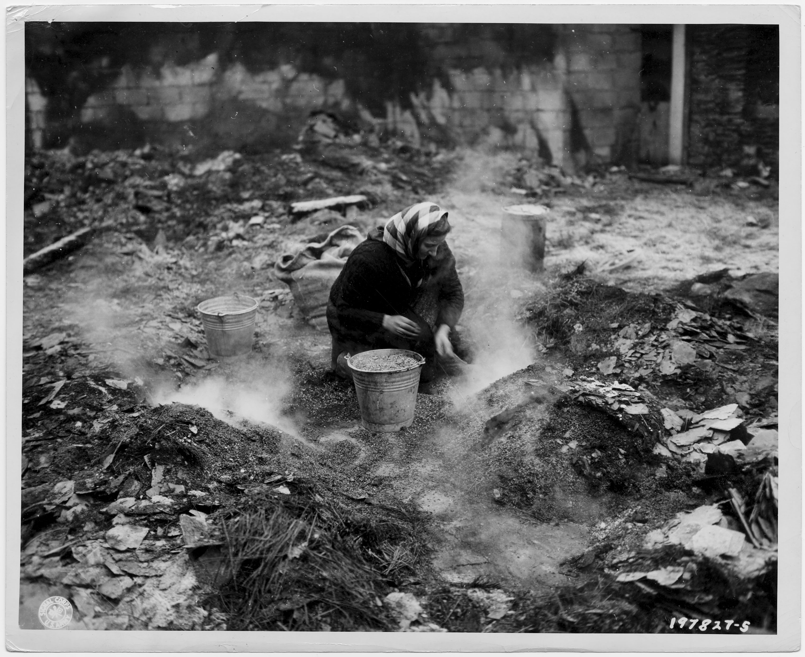 Eine Belgierin sucht Getreidekörner in den Überresten ihrer verbrannten Scheune, 1944